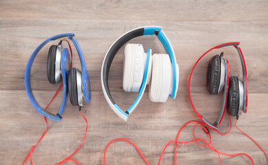 Blue, white, red headphones on the wooden background.