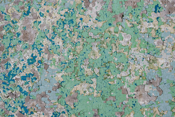 Peeling paint on the wall. Old concrete wall with cracked flaking paint. Weathered rough painted surface with patterns of cracks and peeling. Grunge texture for background and design. High resolution.