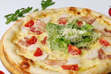 Caesar pizza on board on white wooden table