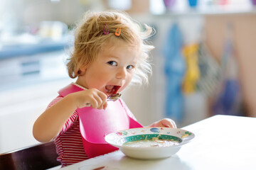 Adorable baby girl eating from spoon vegetable noodle soup. food, child, feeding and development...