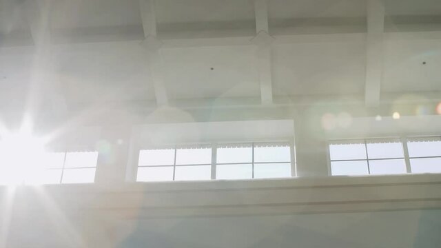 Panorama sun rays shine brightly into the long rectangular windows near the white figured ceiling with cells, creating beautiful highlights