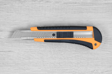 Stationery knife on a background of bleached wood.