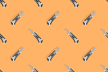 Seamless pattern of stationery knives on an orange background.