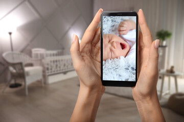 Mother using modern mobile phone as baby monitor at home