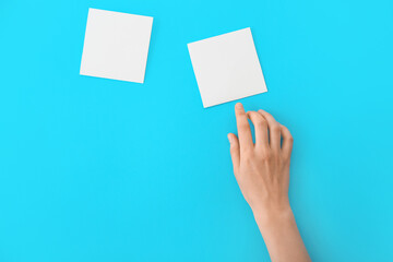 Female hand with blank papers on color background