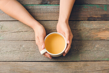 Female hands with cup of green tea on wooden table
