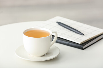 Cup of green tea and notebooks on table