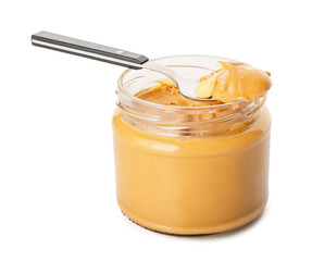 Jar and spoon with tasty peanut butter  on white background