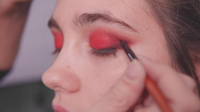 Makeup artist makes eye makeup of the model in the studio.