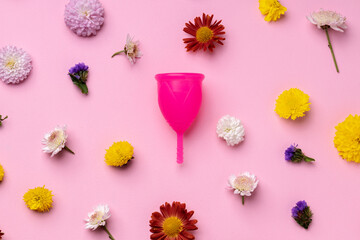 Menstrual cup on floral pattern background top view
