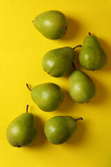 Fresh green pears on yellow background, top view