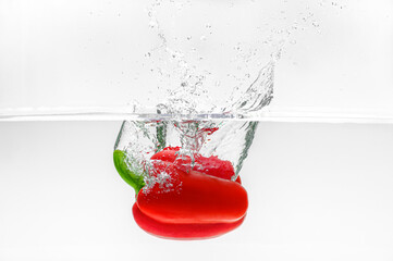beautiful red bell pepper falling into water with beautiful splashes on a white background. Clean healthy vegetables, healthy food