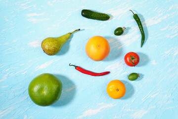 fresh vegetables and fruits cucumber tomato chili pepper tangerine feijoa pear. on a blue background top view