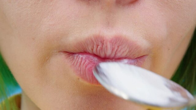 Girl with green hair eats yogurt from a spoon. Close up