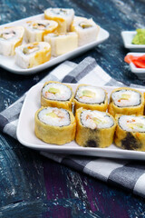 baked sushi rolls with wasabi and ginger on a black background. Japanese oriental cuisine.