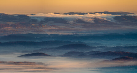 Fototapeta na wymiar Panorama of a mountain valley shrouded in morning mists seen from the top of the Karkonosze mountain range in Poland