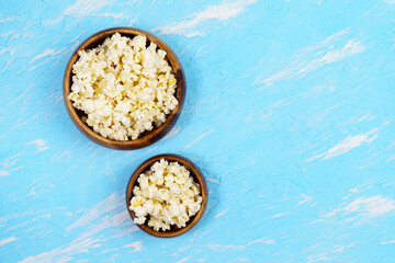 bowls of popcorn small and large portions on a blue background. The concept of leisure and entertainment. copyspace