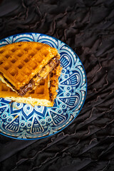 Fresh waffles with peanut butter and chocolate spread on a decorated plate.