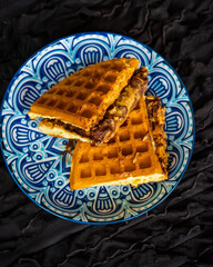 Fresh waffles with peanut butter and chocolate spread on a decorated plate.