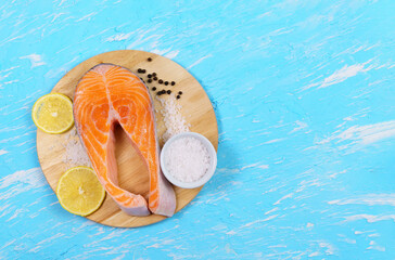 Fish salmon steaks with sea salt and lemon is prepared for cooking. Top view of the blue table....