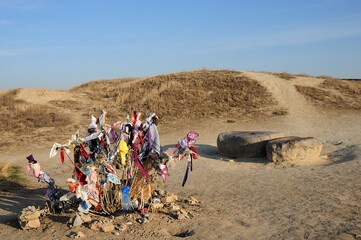 Anav ancient city. A superstition common in Turkmenistan. They believe that when the people tie a cloth to a bush, God will grant their will. Ashgabat, Turkmenistan.