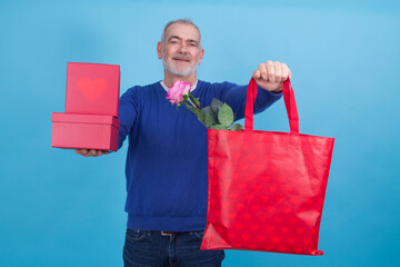 Happy Holidays, my congregations! Portrait of an attractive casual man giving box and bag with rose