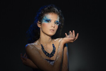 portrait of a beautiful girl with a fantasy winter makeup with ice pieces in her hands