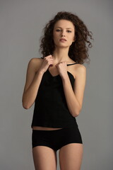Fototapeta premium beautiful girl with curly hair in a black T-shirt and panties posing in the studio
