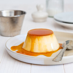 Egg custard in plate with spoon on white background