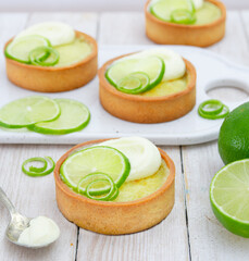 Mini lime pie topped with whipped cream and lime wedges on a light background