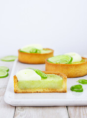 Mini lime pie topped with whipped cream and lime wedges on a light background