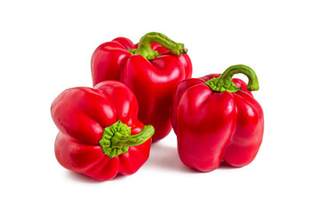 Three red bell peppers with green cuttings on white
