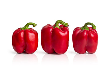 Three ripe red bell peppers on the white surface of the kitchen table
