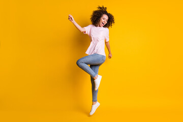 Fototapeta na wymiar Photo portrait full body view of girl jumping up on one leg screaming isolated on vivid yellow colored background