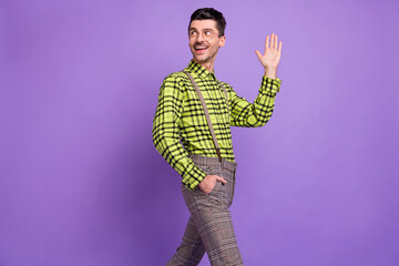 Photo of young happy positive smiling cheerful man walk go say hi look copyspace isolated on violet color background © deagreez