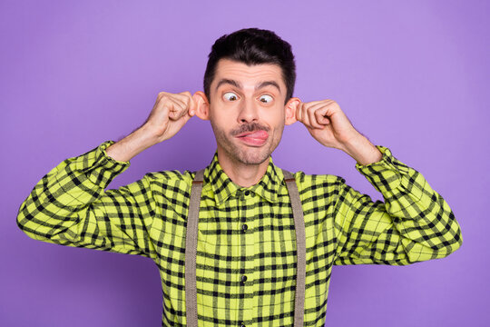 Photo of young funky funny humorous silly childish man stick tongue out pulling ears isolated on purple color background