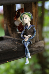 A colorful ceramic doll waiting for the birds in feeder for the birds