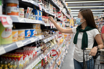 Nakhon Ratchasima, Thailand, 11 Dec 2020: Young Asian women wearing masks are selecting products on the shelves at the supermarket.
