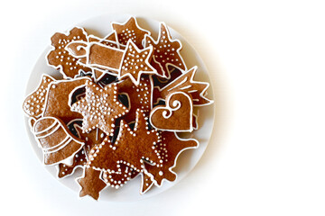 Christmas homemade gingerbread on a plate, handmade, various molds, top view on a white wooden table.