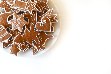 Christmas homemade gingerbread on a plate, handmade, various molds, top view on a white wooden table.