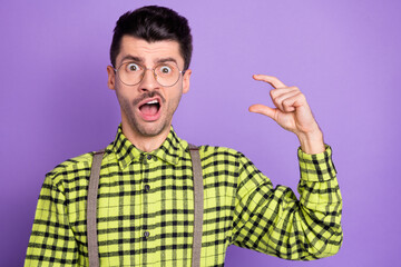 Photo portrait of shocked guy showing small size with fingers isolated on vivid violet colored background