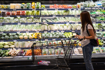 Asian woman is looking for organic vegetable in the shelf at supermarket.
