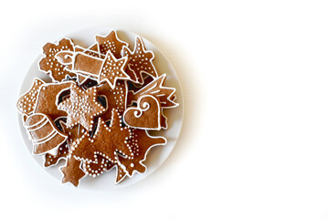 Christmas homemade gingerbread on a plate, handmade, various molds, top view on a white wooden table.