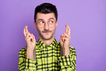 Fototapeta premium Photo portrait of dreamy man with crossed fingers looking at blank space isolated on vivid violet colored background