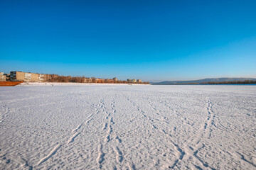 Fototapeta na wymiar Winter icy landscape on a frozen snowy river, footprints visible in the snow