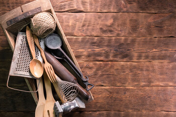 Old kitchen utensils on the brown wooden table background with copy space.