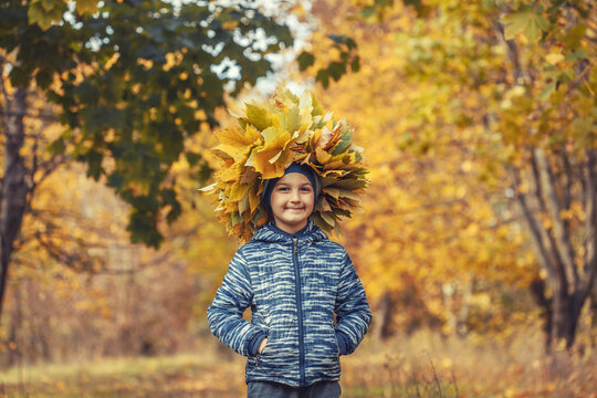 little boy in the autumn forest wearing a wreath of yellow leaves