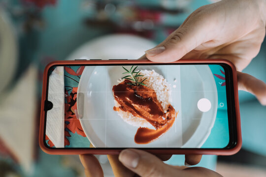 Woman taking pictures on a cell phone on a very tasty plate - Woman uses cell phone to capture her food and share on social networks before eating.