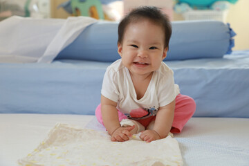 Funny little cute baby smile on the bed in her room