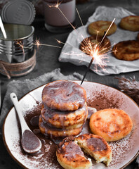 Sweet cottage cheese pancakes. Condensed milk. Festive sweet breakfast or lunch. Dark Grey background. Food and sparklers.